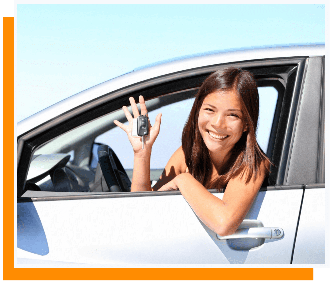 A woman sitting in the drivers seat of her car holding up a key.