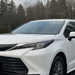 A white car parked in front of some trees